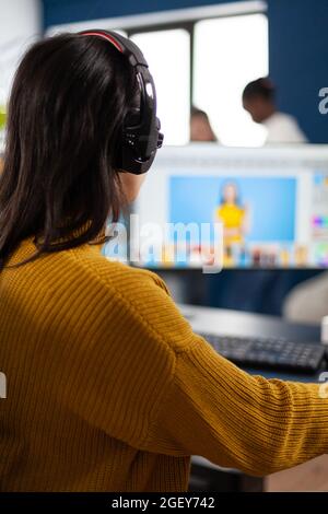 Creative photographer editor retouching photos of a client on performance PC with two displays setup. Woman retoucher working in editing software app sitting office holding stylus pen Stock Photo