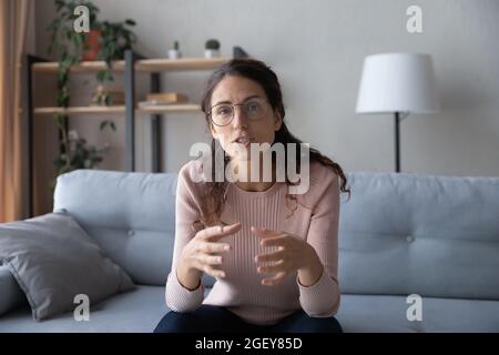 Woman sit on sofa at home talking participating in videocall Stock Photo