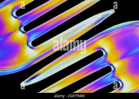 Colourful patterns form on clear plastic forks caused by the refraction of polarised light Stock Photo