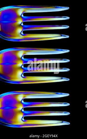 Colourful patterns form on clear plastic forks caused by the refraction of polarised light Stock Photo