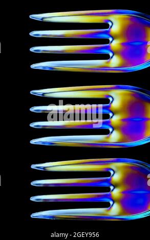 Colourful patterns form on clear plastic forks caused by the refraction of polarised light Stock Photo