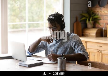 Focused African American student guy in headphones watching learning webinar Stock Photo