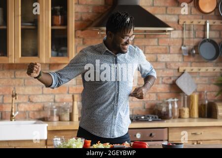 Happy excited Black hipster guy having fun in kitchen Stock Photo