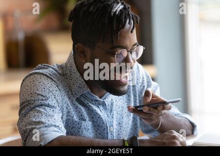 Happy millennial hipster guy using voice recognition app on smartphone Stock Photo