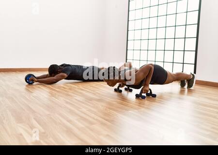 Young african american sporty couple doing push-ups exercise at sport center. Stock Photo