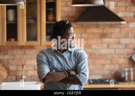 Happy thoughtful African American millennial guy enjoying being at home Stock Photo