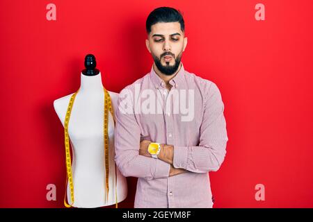 Handsome tailor man with beard with arms crossed gesture making fish face with mouth and squinting eyes, crazy and comical. Stock Photo