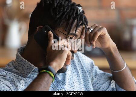 Thoughtful concerned millennial African guy making telephone call Stock Photo