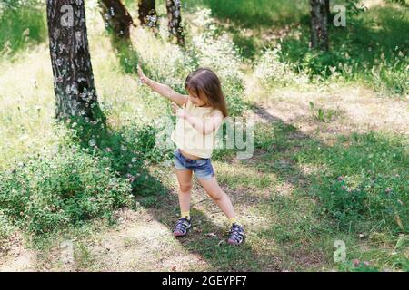 happy caucasian child girl in a yellow t-shirt catches a lot of soap bubbles on a summer day. outdoor activity Stock Photo
