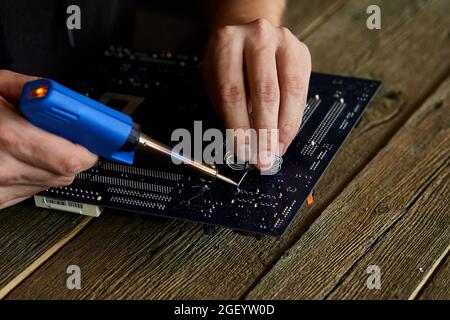 Engineer or technician repair electronic circuit board with soldering iron. Man hands soldiers computer circuit board using soldering iron. Copy space Stock Photo
