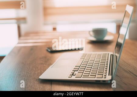 Home office workspace, laptop and smartphone on the desk in working from home concept, selective focus Stock Photo