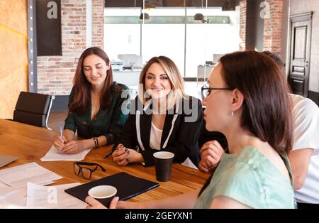 Group of young successful people business professionals having meeting in boardroom, four office workers discussing new project together while sitting Stock Photo