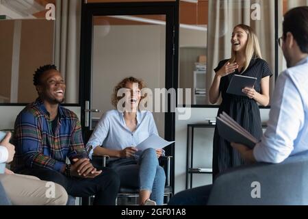 Smiling multiethnic colleagues laugh talking at meeting Stock Photo