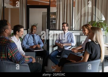 Smiling diverse employees laugh at team office meeting Stock Photo