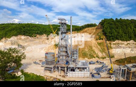 Cement factory at open pit mining of construction sand stone materials with excavators and dump trucks. Stock Photo