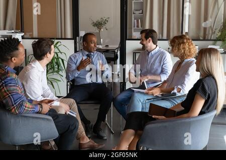 Multiethnic employees discuss ideas at team meeting Stock Photo