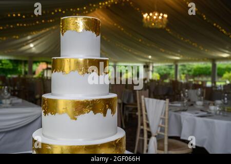 Four tier wedding cake with gold leaf and fresh flowers Stock Photo - Alamy