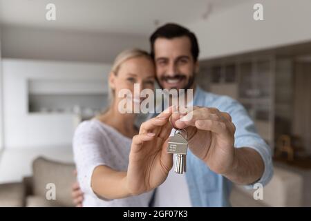 Happy proud millennial couple holding, showing keys, smiling at camera Stock Photo