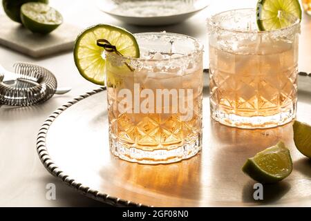 Margarita cocktails with salted rims on a metal tray with ingredients and strainer in behind. Stock Photo