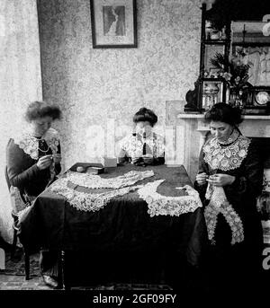 An early 20th century scene of tthree women making Carrickmacross Lace in their house in County Monaghan. It was introduced into Ireland in about 1820 by one Mrs Grey Porter of Donaghmoyne, who taught it to local women so that they could earn some extra money. Porter had been inspired by some examples of appliqué lace she had seen while on her honeymoon in Italy. Stock Photo