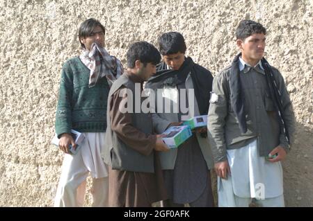 Young local Afghan men receive radios as Humanitarian Assistance  from Afghanistan national security forces members as part of a training mission at Khanjarkhe, Parwan province, Afghanistan during a training mission. ANSF commandos take part in in their first training mission as they attend the ANSF Air Assault Academy at Bagram Airfield, Afghanistan, March 10. Stock Photo