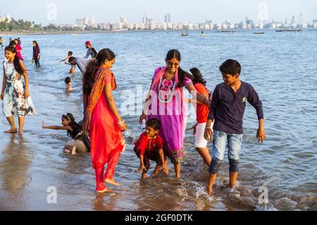 Mumbai, Maharashtra, India : People relax at Girgaon Chowpatty beach. Marine drive and Nariman Point in background. Stock Photo