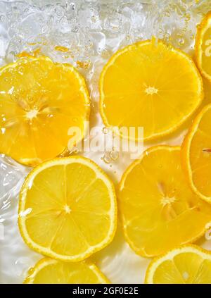 Close-up fresh slices of yellow lemon on white background. Slices of lemon in sparkling water on white background, closeup. Citrus soda Stock Photo