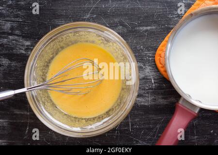 Top view of yolks, starch and sugar mix in bowl as ingredient to make custard cream on black background Stock Photo