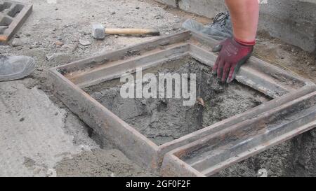 Workers making base for sewer grill. Bulding worker using water level. Bulding worker concept Stock Photo