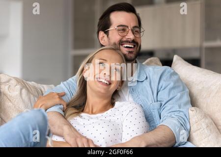 Happy joyful married couple resting and hugging on sofa Stock Photo