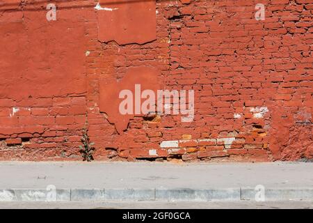 old brick wall with peeled off plaster, all over painted orange Stock Photo