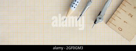 Wooden ruler, compasses and pencil lie on graph paper Stock Photo