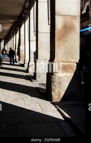 Walking in the shade of the arcaded walkway in the Calle de Toledo, central Madrid, Spain Stock Photo