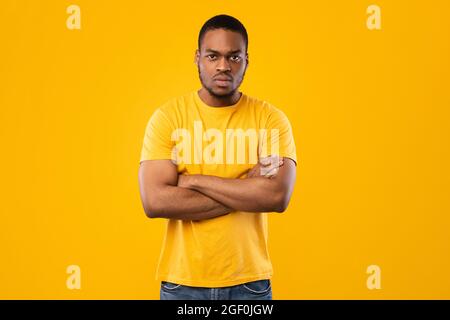 Serious African American Man Posing Crossing Hands Over Yellow Background Stock Photo