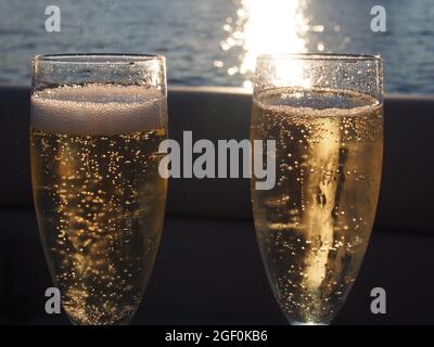 Sunlit Champagne Toast with Sparkling Bubbles Against a Lake Sunset Stock Photo