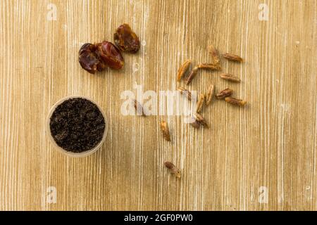 Top view of cup with soil, dates fruit and bones for planting palm on wooden background Stock Photo