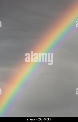 Colourful rainbow in a dark grey stormy sky Stock Photo