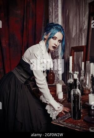 Indoors portrait of gorgeous goth girl in black skirt and white shirt. Blue-haired gothic lady. Vintage look Stock Photo