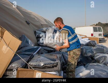 A U.S. service member unloads and breakdown boxes of bedding for qualified evacuees Aug. 21, 2021, at an undisclosed location somewhere in Southwest Asia. As part of the evacuation of Afghanistan, the evacuees departed Hamid Karzai International Airport, Kabul, Afghanistan on multiple military aircraft. (U.S. Air Force photo by Staff Sgt. Kylee Gardnervia American PhotoArchive/ALAMY) Stock Photo