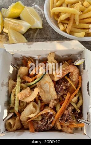 Mixed fried fish with potatoes and lemon. Directly above. Stock Photo