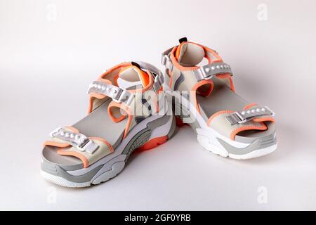 Women's, fashionable, sports sandals with orange accents on a white background. New youth shoes for girls. Front view. Stock Photo