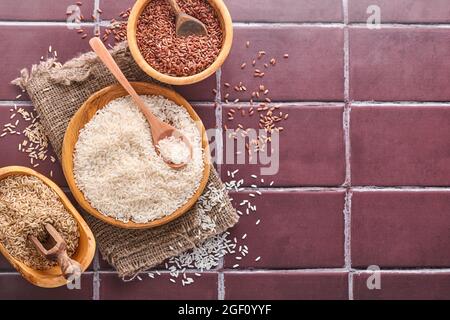 Rice, Jasmine, Brown, Red, Black in a wooden bowl on a brown stone kitchen table. Gluten-free cereals. Top view with copyspace. Stock Photo