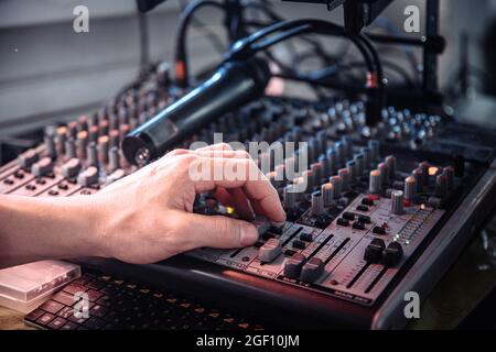 the DJ's hand touches the audio control panel at shallow depth of field Stock Photo
