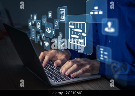 Project manager working on computer at the office. Concept with icons of management areas such as cost, planning, risks, schedule. Person typing on ke Stock Photo