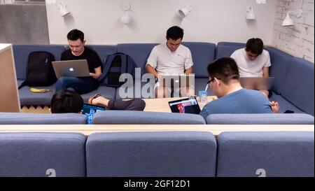 Group of five male friends socializing and playing network video games on laptops in the lobby or cafe Stock Photo