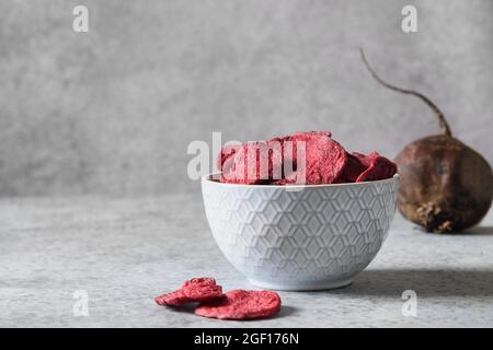 Vegetable vegan beetroot chips in bowl on a gray background. Vegan snack. Close up. Home drying. Stock Photo