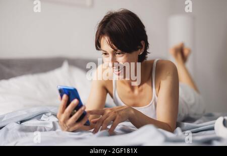 Woman using smartphone in bed Stock Photo