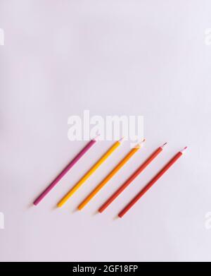 composition of colored pencils with red and yellow tones lined up on a white background with back to school concept copy space Stock Photo