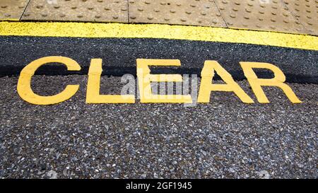 A loudly written yellow sign on a platform to CLEAR people away from the edge and in a safe area Stock Photo