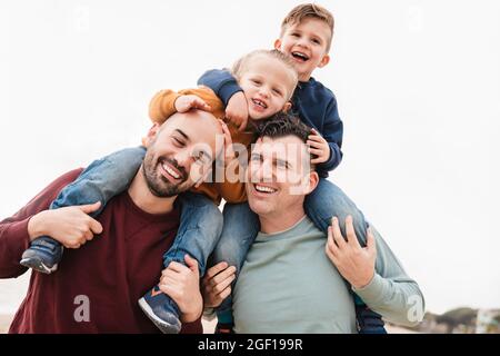 Gay fathers and sons playing together outdoor in the city - LGBT family love concept - Focus on right dad face Stock Photo